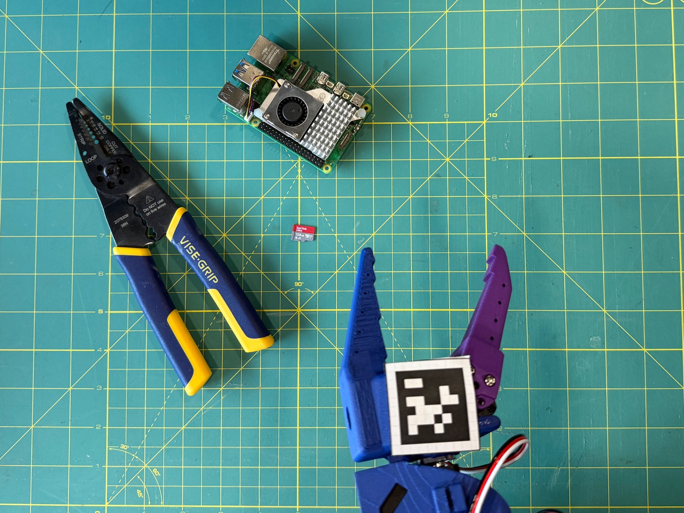 A Vise-Grip-shaped tool, a Raspberry Pi 5, and a microSD card, arranged on the workbench